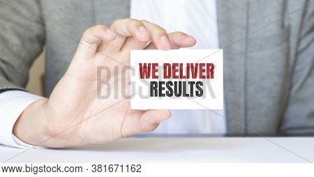 Businessman Holding A Card With Text We Deliver Results