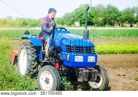 A Farmer Drives A Tractor While Working On A Farm Field. Loosening Surface, Cultivating The Land. Fa