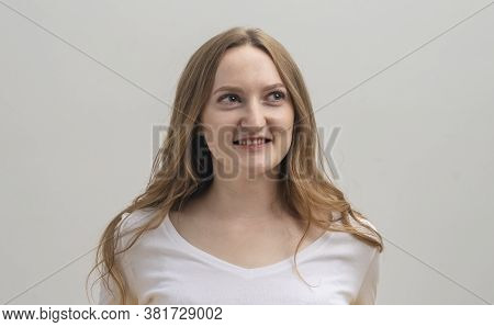Young Caucasian Woman Interested In Coversation And Looking Aside Over Grey Background, Studio
