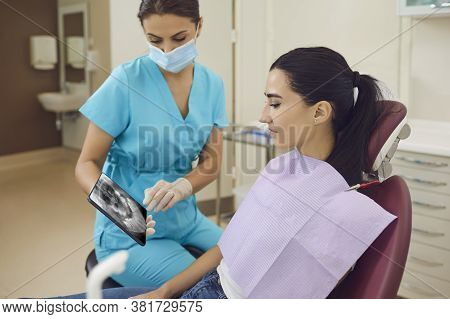 Dentist Showing Panoramic X-ray Snapshop Of Teeth To Woman Patient