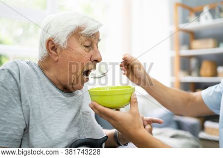 Hungry Elder Patient Being Feed At Nursing Home