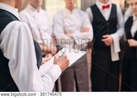 Restaurant Manager And His Staff In Kitchen. Interacting To Head Chef In Commercial Kitchen.