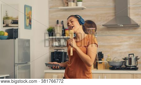 Cheerful Woman Singing On Wooden Spoon In The Morning Listening Music On Headphones. Energetic, Posi