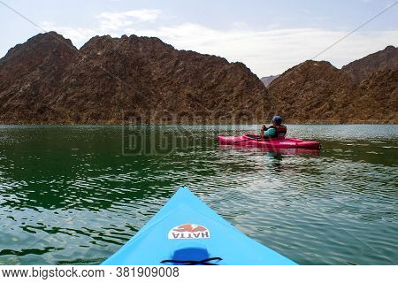 Hatta / Uae - July 18, 2020: Young Man Is In A Pink Kayak In The Middle Of 
Hatta Lake And Colorful 