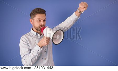 Young Caucasian Man Screaming Into The Loudspeaker Isolated On The Blue Background. Slow Motion.