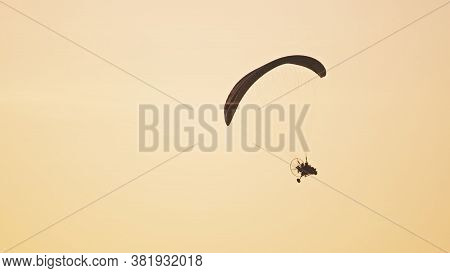 Silhouette Of The Paramotor Tandem Gliding And Flying In The Air. Copy Space High Quality Photo