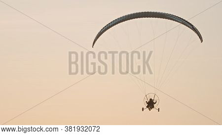 Silhouette Of The Paramotor Tandem Gliding And Flying In The Air. Copy Space High Quality Photo
