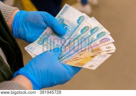 A Man Holds Russian Money In A Fan, Wearing Blue Medical Gloves. Payment For Products. Cropped Shot,