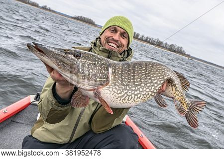 Success Pike Fishing. Happy Fisherman With Big Fish Trophy At Boat On Background Of Skewed Horizon L