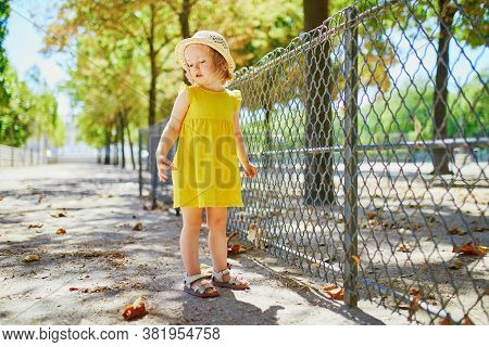 Unhappy And Emotional Toddler Girl In Park. Misbehaving Child Outdoors. Terrible Twos And Kid Tantru
