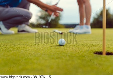 Pro on golf course teaching a woman how to put, close-up