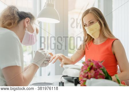 Woman in the nail salon receiving manicure wearing a face mask during coronavirus crisis