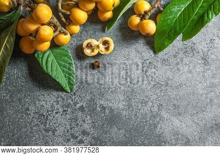 Fresh Ripe Loquat Japanese Medlar Fruit With Branch And Leaf On Rustic Background, Malta Plum, Summe