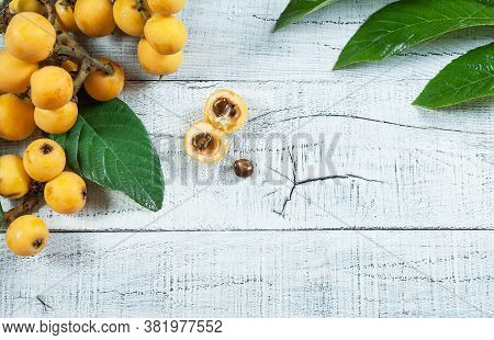 Fresh Ripe Loquat Japanese Medlar Fruit With Branch And Leaf On Rustic Background, Malta Plum, Summe