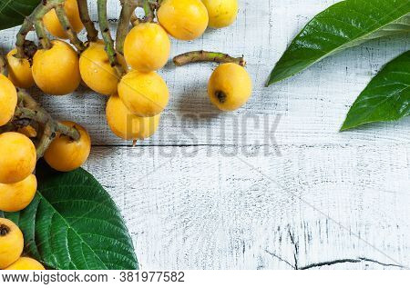 Fresh Ripe Loquat Japanese Medlar Fruit With Branch And Leaf On Rustic Background, Malta Plum, Summe