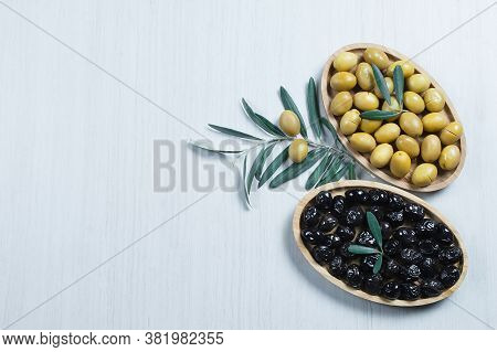 Raw Turkish Green And Black Olive Seeds In Bamboo Bowl And Olive Tree Leaves On White Table. Olives 