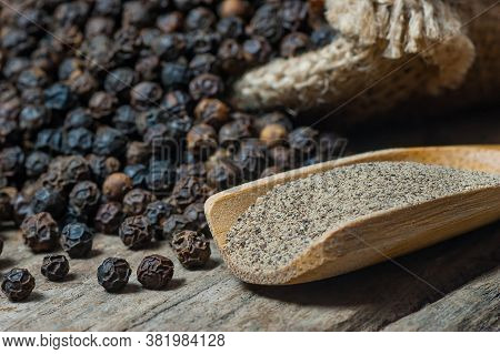 Heap Of Black Pepper And Black Pepper Powder In Wooden Spoon, Milled Peppercorns On Wooden Backgroun