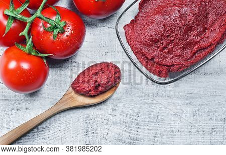 Tomato Paste In Wooden Spoon And Ripe Fresh Grape Tomatoes On Wooden Background. Cherry Tomatoes. To