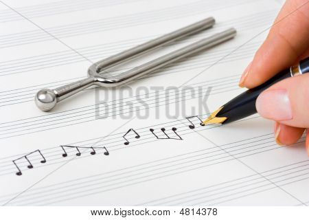 Main avec le stylo et la feuille de musique