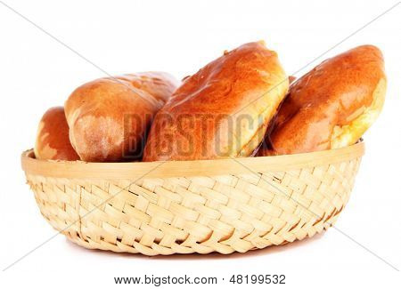 Empanadillas al horno frescos en cesta de mimbre, aislados en blanco
