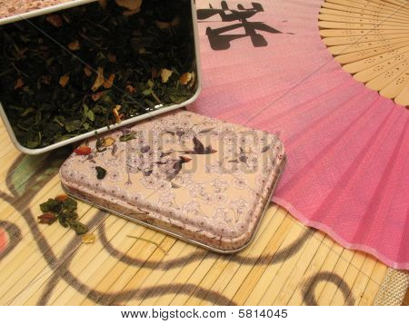 Green fruit tea in tin and Chinese fan