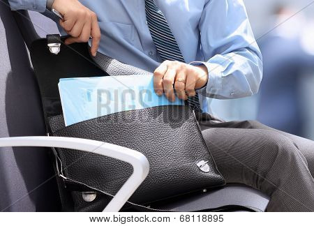 Businessman Siting On A Chair And Geting Out   Documents With Graphs  From The  Leather Briefcase.