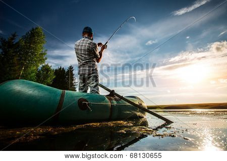 Mature man fishing from the boat at sunset