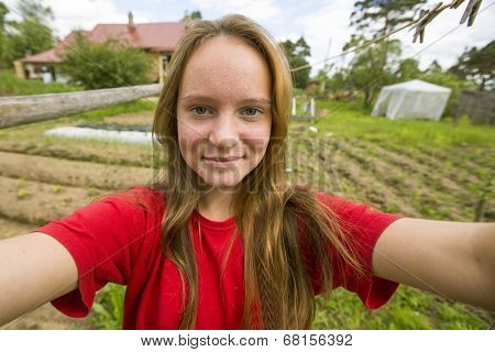 Teengirl taking a self-portrait out in the country house.
