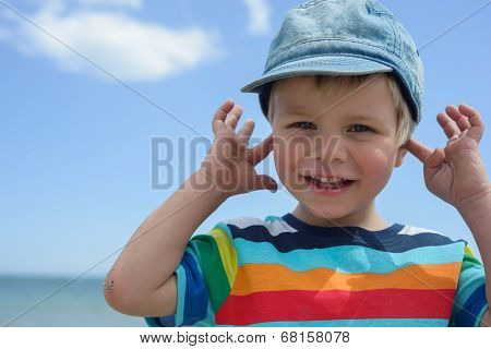 Small boy holds his hands over ears not to hear