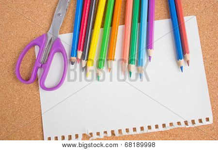 Blank paper, color pencil and scissors on wooden board.