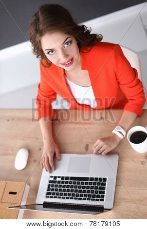 Attractive woman sitting at desk in office, working with laptop