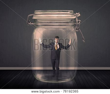 Businessman trapped into a glass jar concept on background