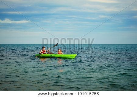 Kayaks. Couple kanoeing in the sea near the island with mountains. People kayaking in the ocean.