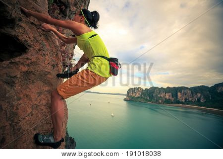 young woman rock climber climbing on cliff