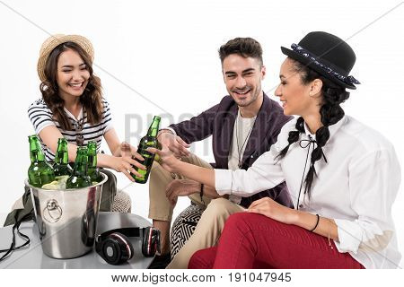 Happy young frinds sitting together at table and drinking beer isolated on white