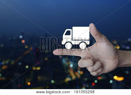 Truck delivery icon on finger over blur colorful night light city tower Transportation business concept