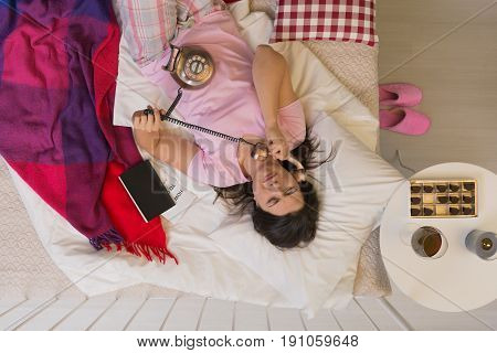 Worried woman in pajamas with a phone in bed