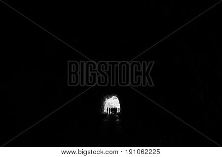 People are in a dark tunnel in the rock silhouettes on a light background input