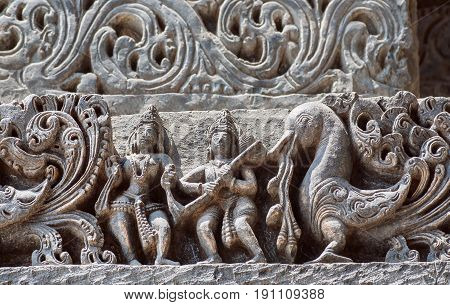 Background in Indian raditional style with reliefs and fantasy bird and ancient people. Interior of the 12th century Hoysaleshwara temple in Halebidu, Karnataka state, India