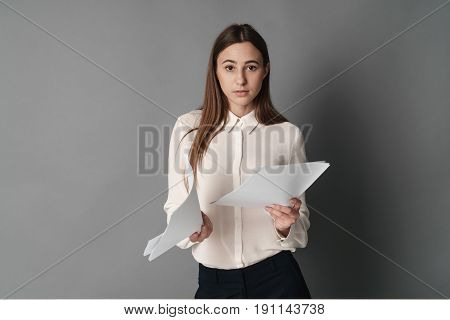 Businesswoman in perplexity reading documents. One is isolated on a gray background.