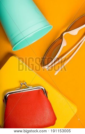 Sunglasses , purse , notebook and  cup on the yellow background top view vertical