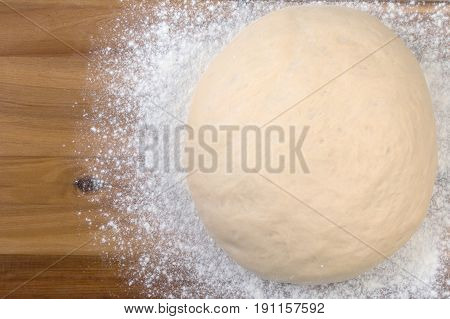 Ball A Dough And White Flour On A Wooden Cutting Board. Top View, Close Up.