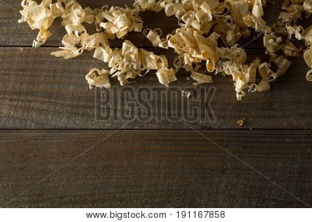 Light brown wood shavings from carpenter's hand planer or chisel work on wooden boards background with copy space