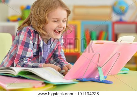 Portrait of a smilimg little girl reading book