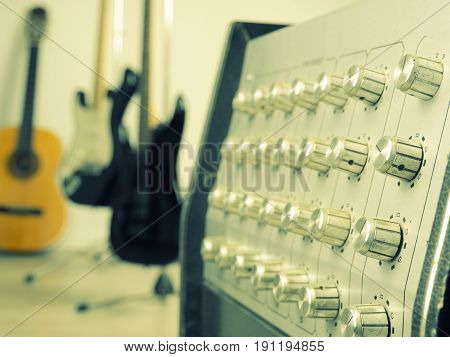 Close up of a vintage amplifier with three guitars in a studio retro film toned