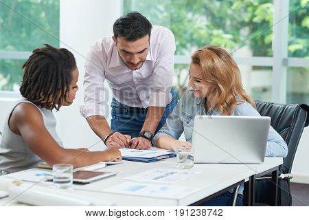 Bearded businessman presenting his ideas to pretty female colleagues while having productive working meeting in spacious boardroom