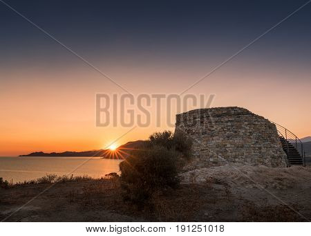 Orange & pink glow before the sun rises at dawn behind the Genoese tower at Lozari on the coast of the Balagne region of Corsica