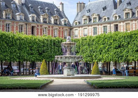 Paris, France - May 13, 2017: People around a fountain on place des vosges