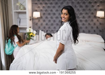 Portrait of smiling nurse standing by patient on bed at home