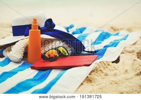 bag, suncream, glasses and touch pad on tropical beach
